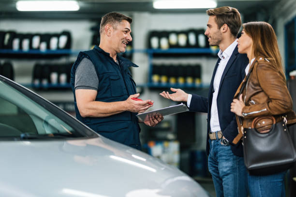 A happy mechanic is having communication with a couple in mechanic's shop