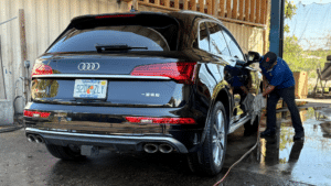 A skilled technician performs a detailed diagnostic inspection on a sleek Audi in a modern service bay.
