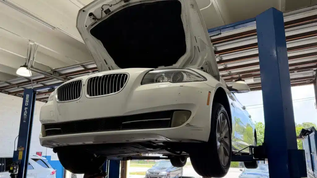 White BMW on a vehicle lift undergoing professional repair and diagnostic service