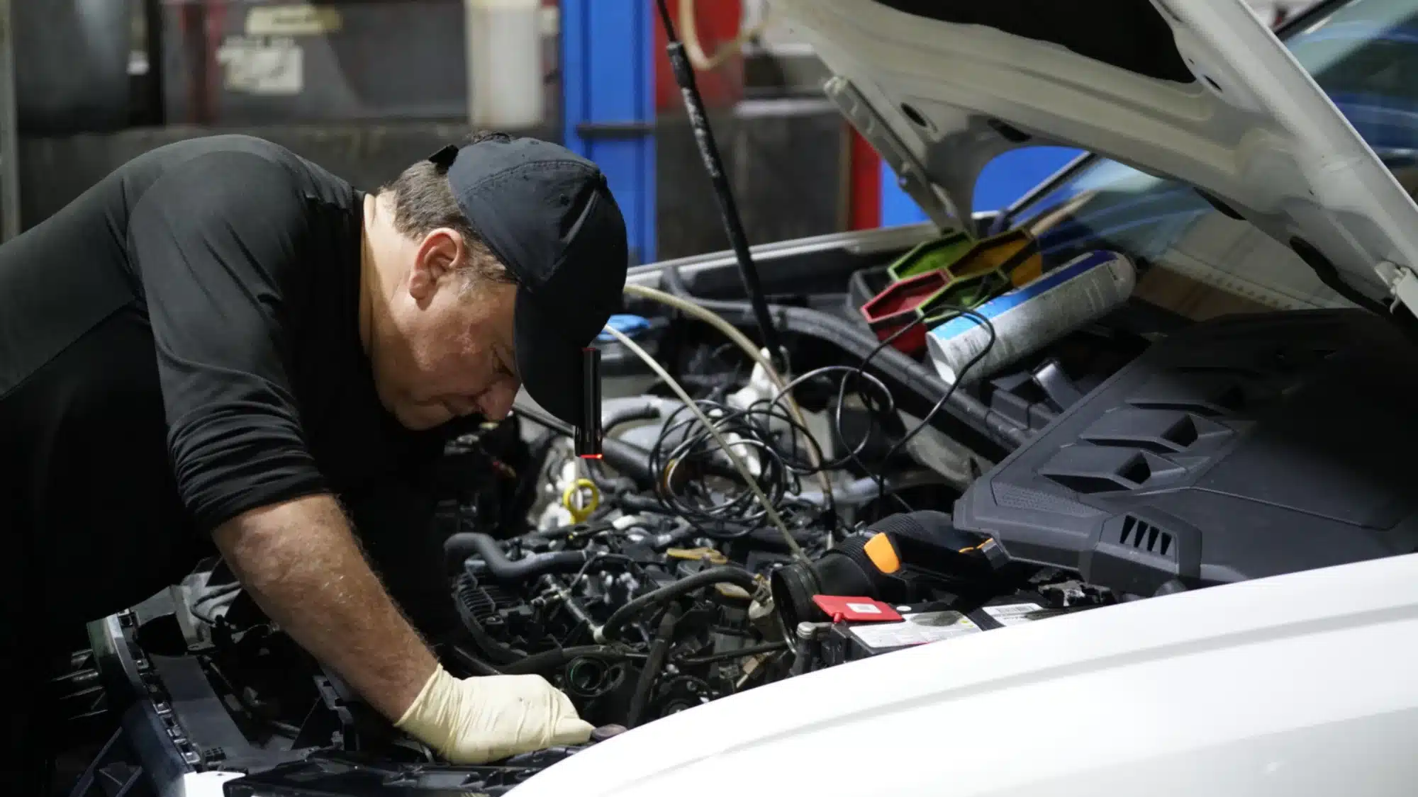 A skilled technician performing routine maintenance on a shiny Mercedes-Benz in a professional service bay.