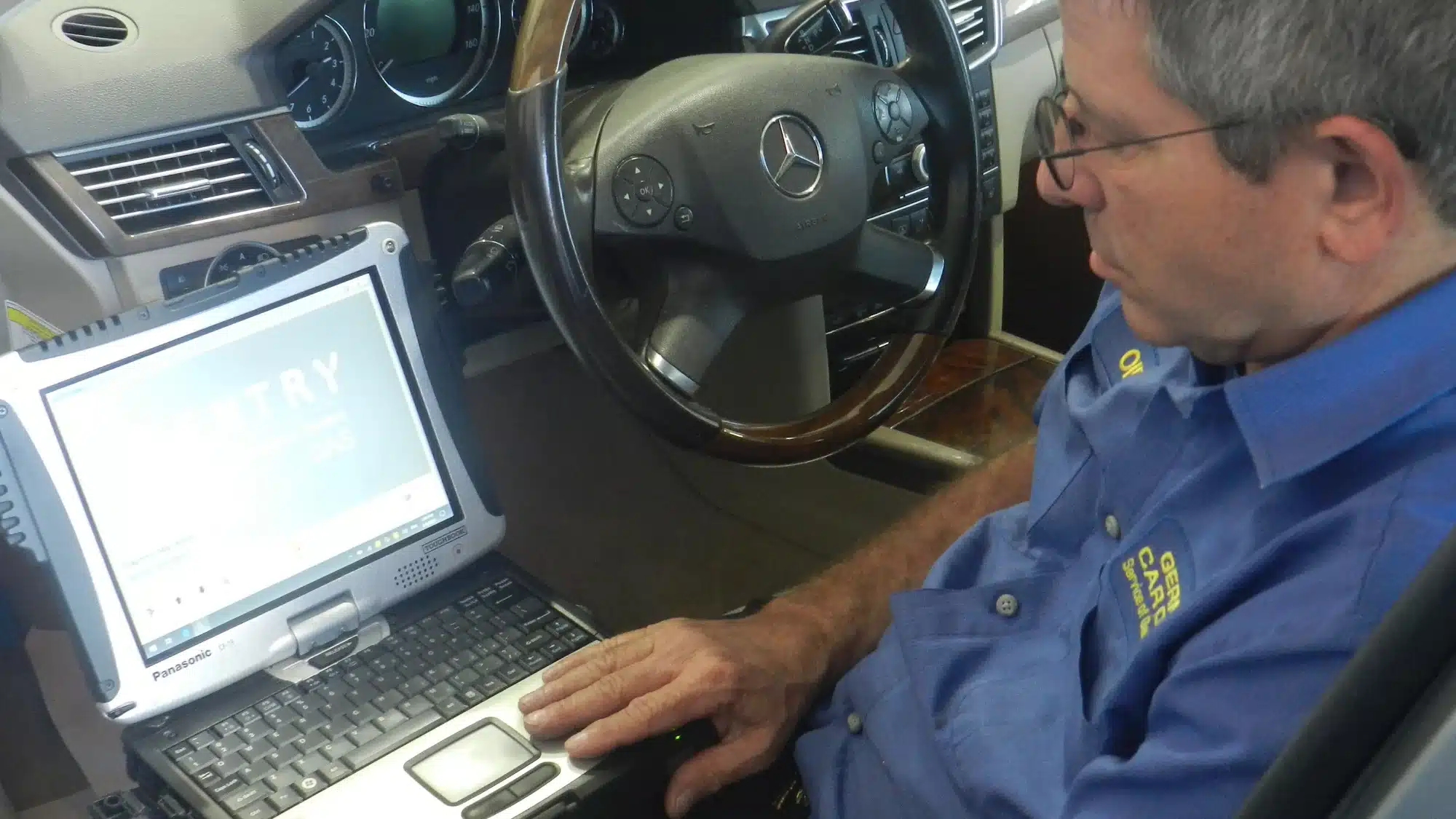 German Car Depot mechanic using diagnostic equipment to inspect a Mercedes-Benz for professional repair and service.